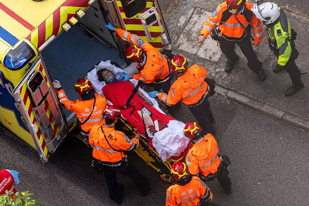 Health workers evacuate a woman from a fire which broke out at Wang Fuk Court, a residential estate in the Tai Po district of Hong Kong's New Territories, Thursday, November 27, 2025. (AP Photo/Chan Long Hei)