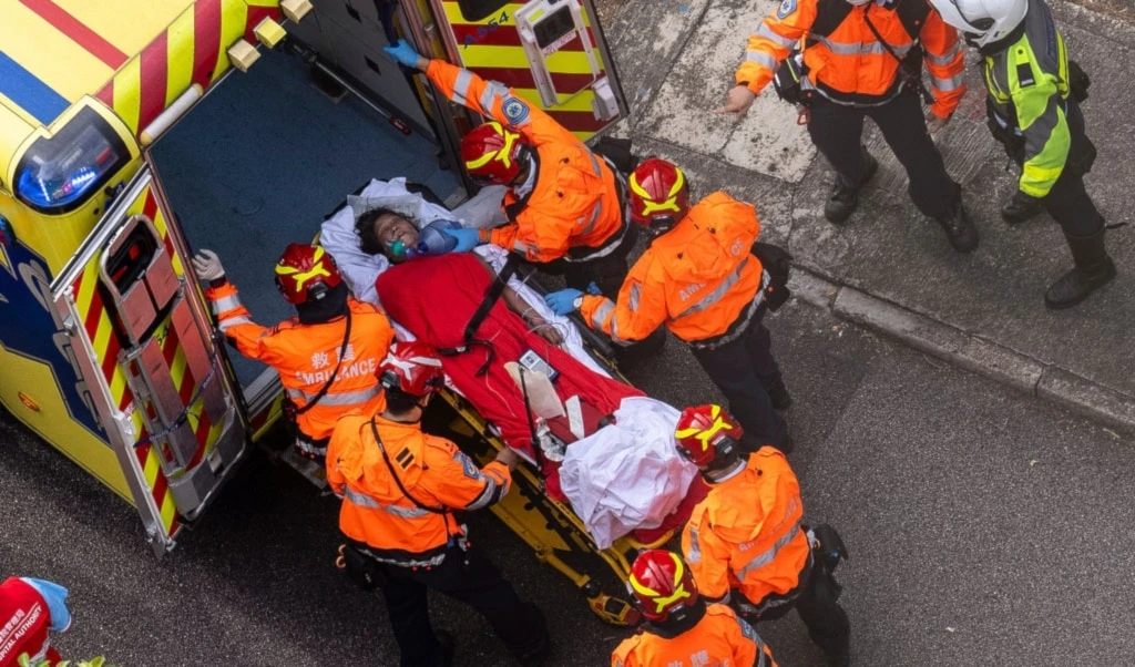 Health workers evacuate a woman from a fire which broke out at Wang Fuk Court, a residential estate in the Tai Po district of Hong Kong's New Territories, Thursday, November 27, 2025. (AP Photo/Chan Long Hei)