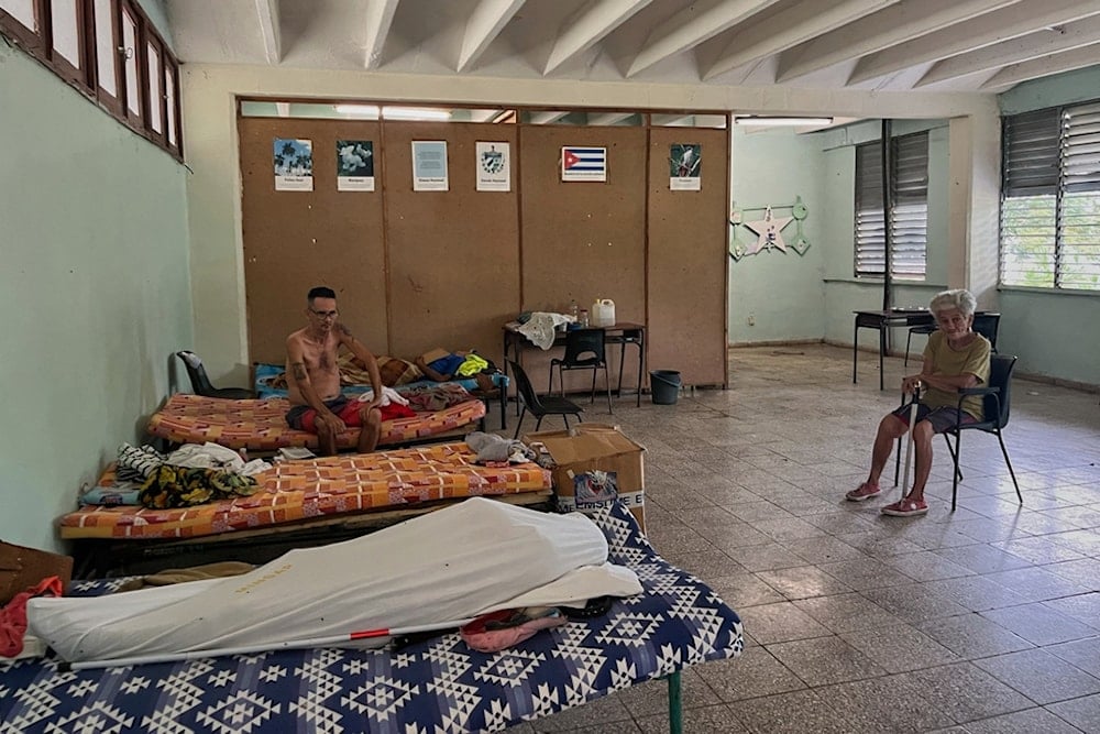 People displaced by Hurricane Melissa sit in a shelter in Los Mangos, Cuba, Monday, November 17, 2025. (AP Photo/Milexsy Duran)