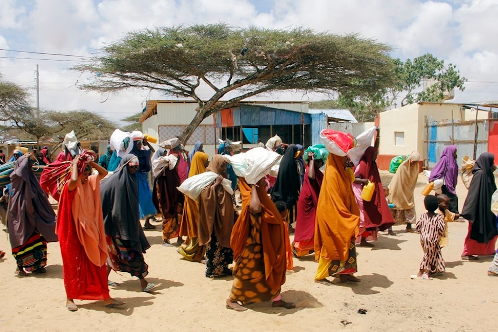 Somalis, who fled amid drought, carry their belongings as they arrive at a makeshift camp on the outskirts of the capital Mogadishu, Somalia, Tuesday, September 26, 2023. (AP Photo/Farah Abdi Warsameh)