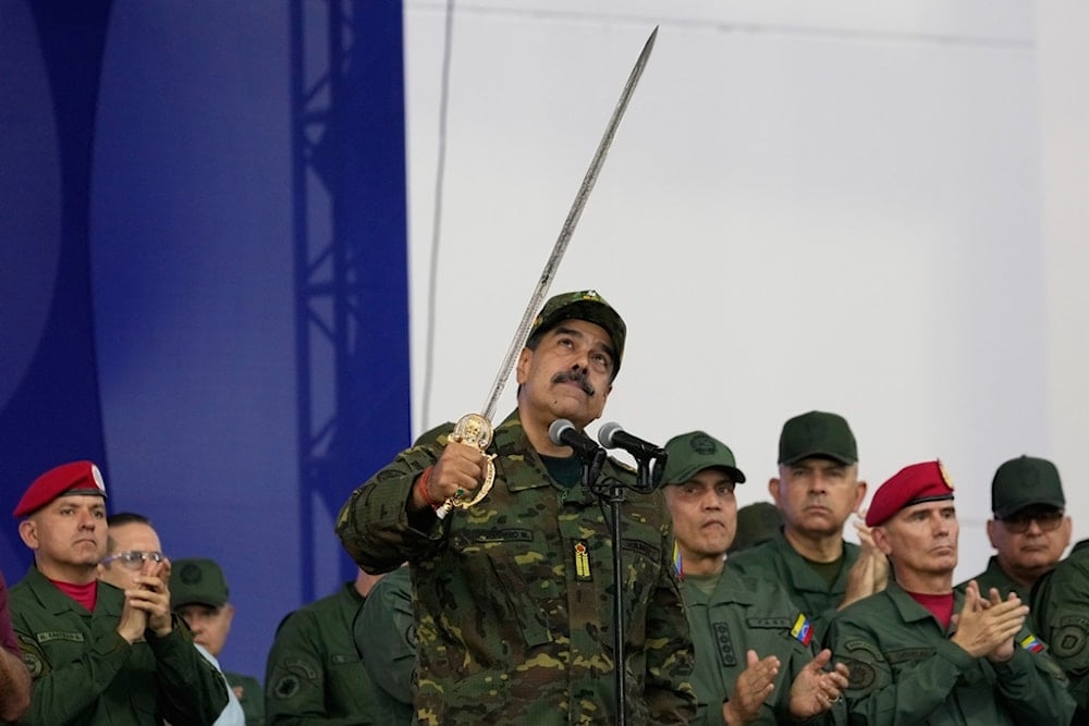 Venezuelan President Nicolas Maduro brandishes a sword said to have belonged to independence hero Simon Bolivar during a civic-military event at the military academy in Caracas, Venezuela, Tuesday, November 25, 2025. (AP Photo/Ariana Cubillos)