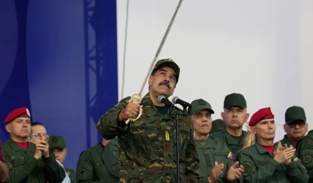 Venezuelan President Nicolas Maduro brandishes a sword said to have belonged to independence hero Simon Bolivar during a civic-military event at the military academy in Caracas, Venezuela, Tuesday, November 25, 2025. (AP Photo/Ariana Cubillos)