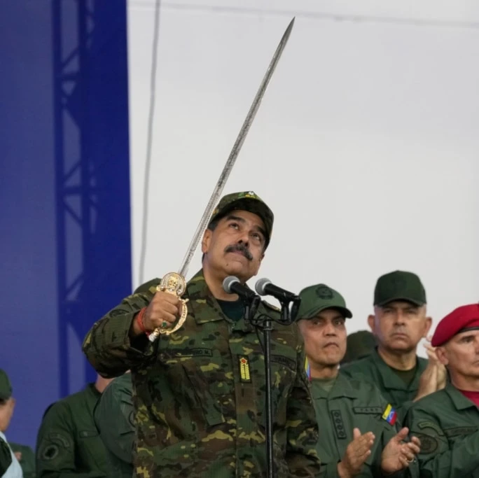 Venezuelan President Nicolas Maduro brandishes a sword said to have belonged to independence hero Simon Bolivar during a civic-military event at the military academy in Caracas, Venezuela, Tuesday, November 25, 2025. (AP Photo/Ariana Cubillos)