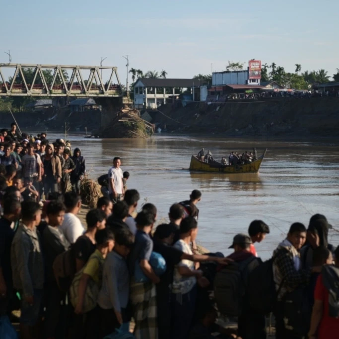 People wait for a boat to ride across a river after a bridge nearby collapsed during a flood in Bireun, Aceh province, Indonesia, Saturday, November 29, 2025 (AP)