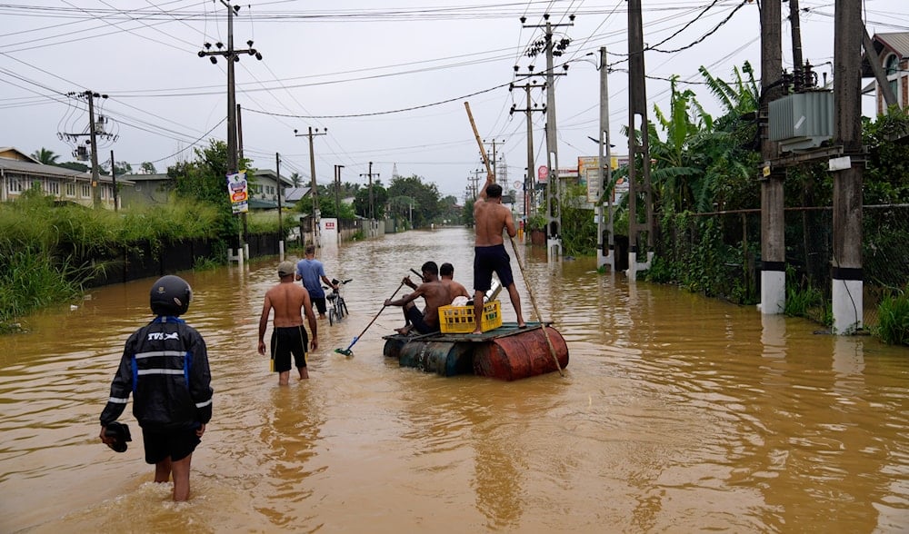 People use a crude raft to navigate a flooded street in Colombo, Sri Lanka, on November 29, 2025. (AP Photo/Eranga Jayawardena)