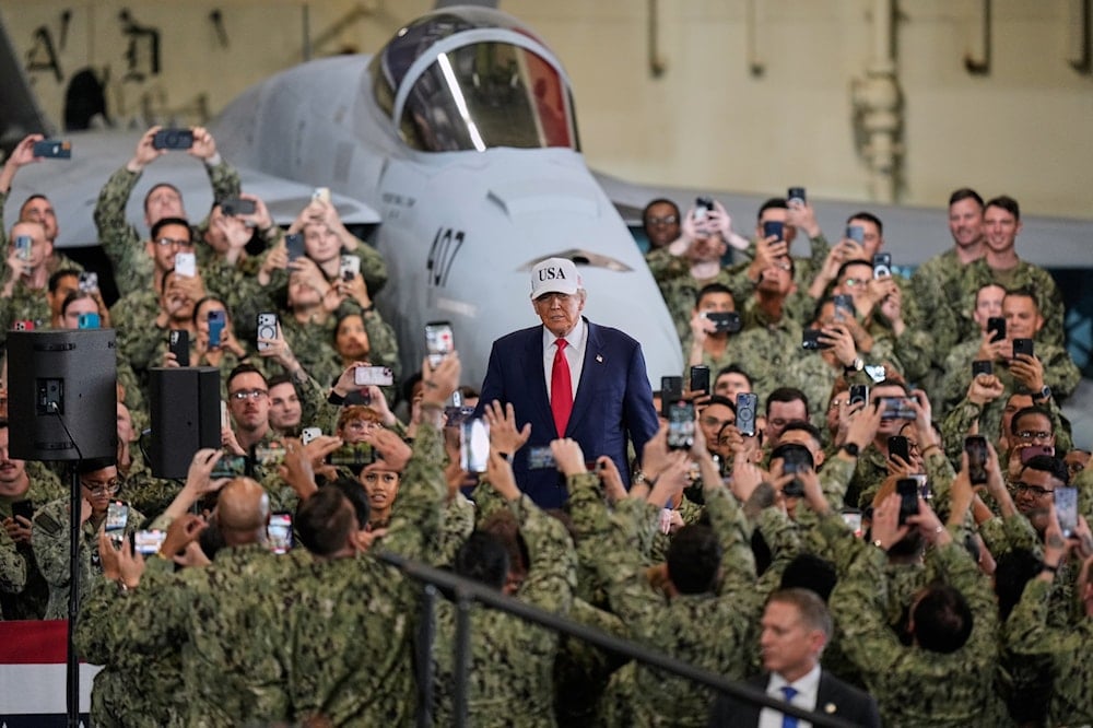 US soldiers use smartphones to film US President Donald Trump as he arrives to the aircraft carrier USS George Washington at the US Navy's Yokosuka base, in Yokosuka, south of Tokyo, Tuesday, October 28, 2025 (AP)