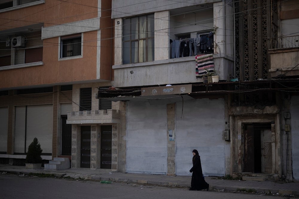 A woman walks on a street in an Alawite neighbourhood, in Homs, Syria, Thursday, Dec. 26, 2024 (AP)