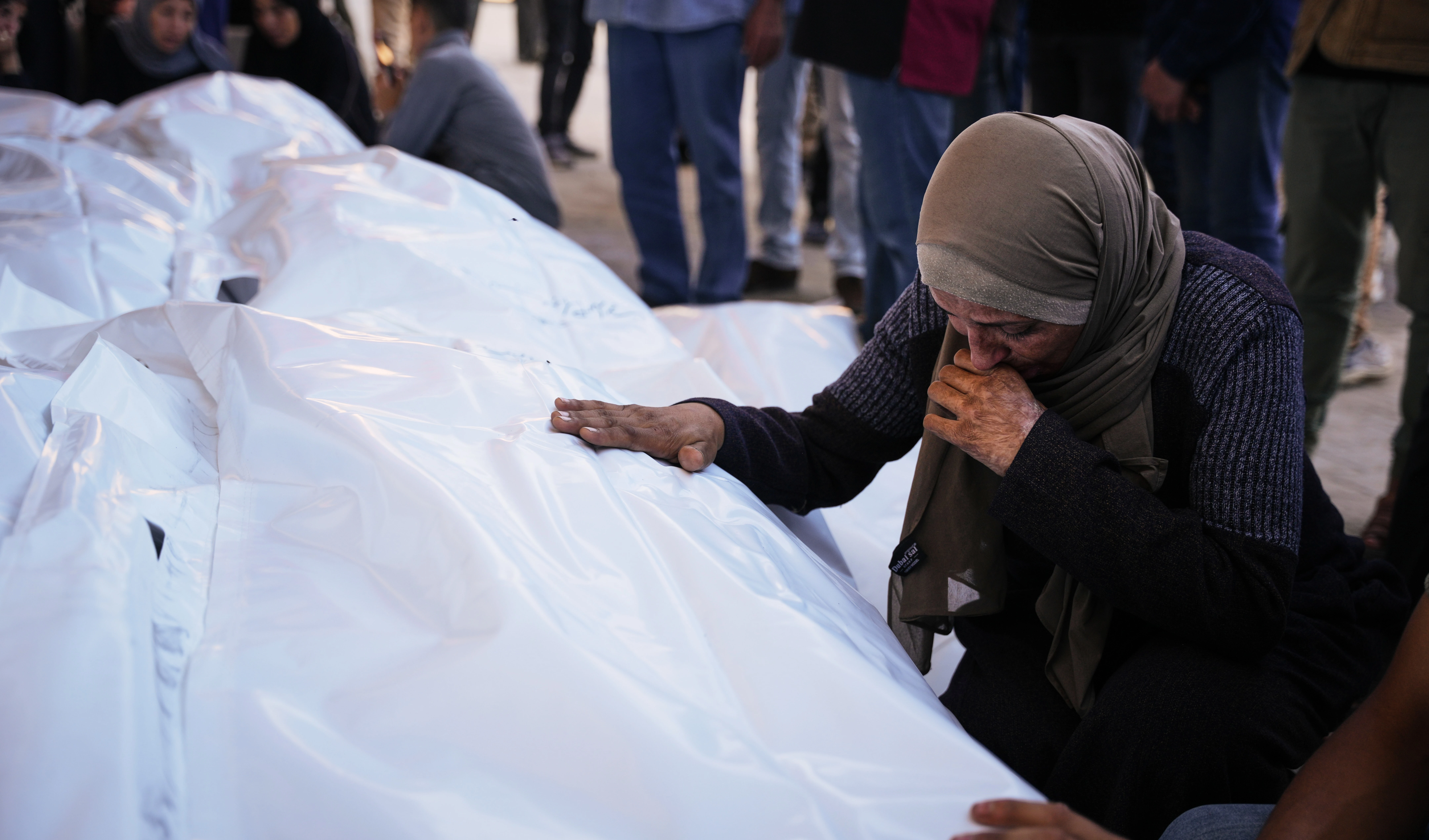 Ahmed Al-Bohisi mourns over the body of his cousin, Mohammad Abu Shawish, 18, who was killed in an Israeli military strike, during his funeral at Al-Aqsa Hospital in Deir al-Balah in the Gaza Strip, on November 23, 2025. (AP Photo/Abdel Kareem Hana)