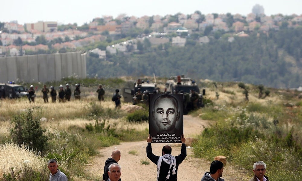 A placard of Nasser Abu Srour is held aloft during a 2015 demonstration marking Palestinian Prisoner Day in the West Bank town of Bilin, near Ramallah. (Abbas Momani/AFP/Getty Images)