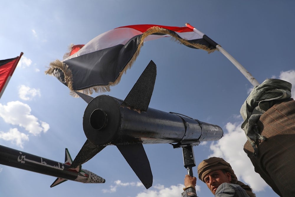An Ansar Allah supporter chants slogans as he carries a rocket replica during an anti-US, anti-'Israel' rally in Sanaa, Yemen, following Israeli airstrikes in Sanaa, Yemen, Friday, Sept. 26, 2025 (AP)