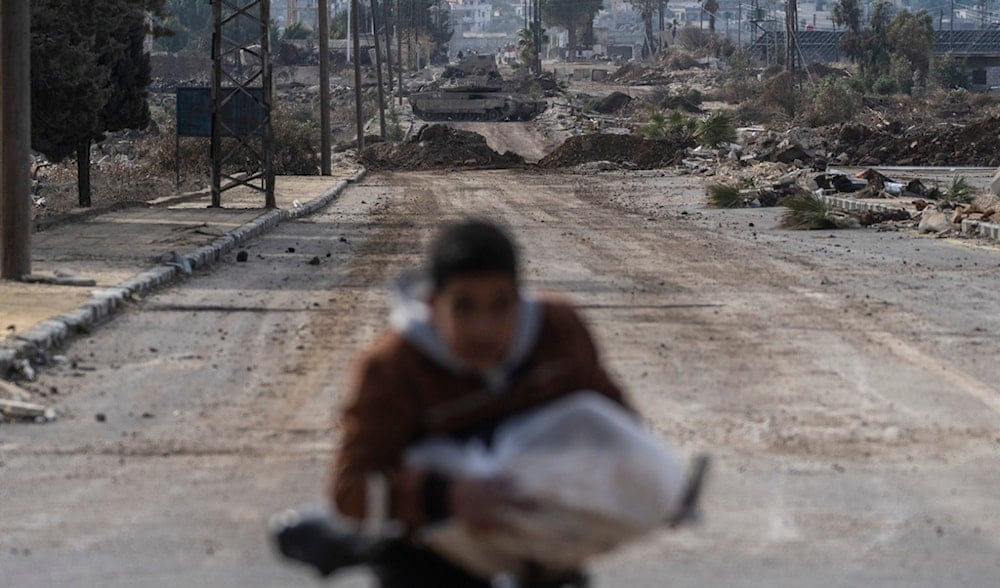 A boy carrying bread cycles home as Israeli military armored vehicles block a road leading to the town of Quneitra, Syria, Sunday, Jan. 5, 2025. (AP)