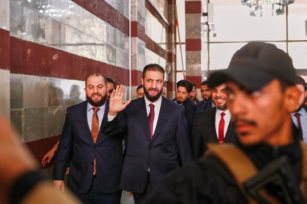 Syrian interim President Ahmad al-Sharaa waves as he enters a polling station where electoral college members are voting in a parliamentary election in Damascus, Syria, Sunday, October 5, 2025 (AP)