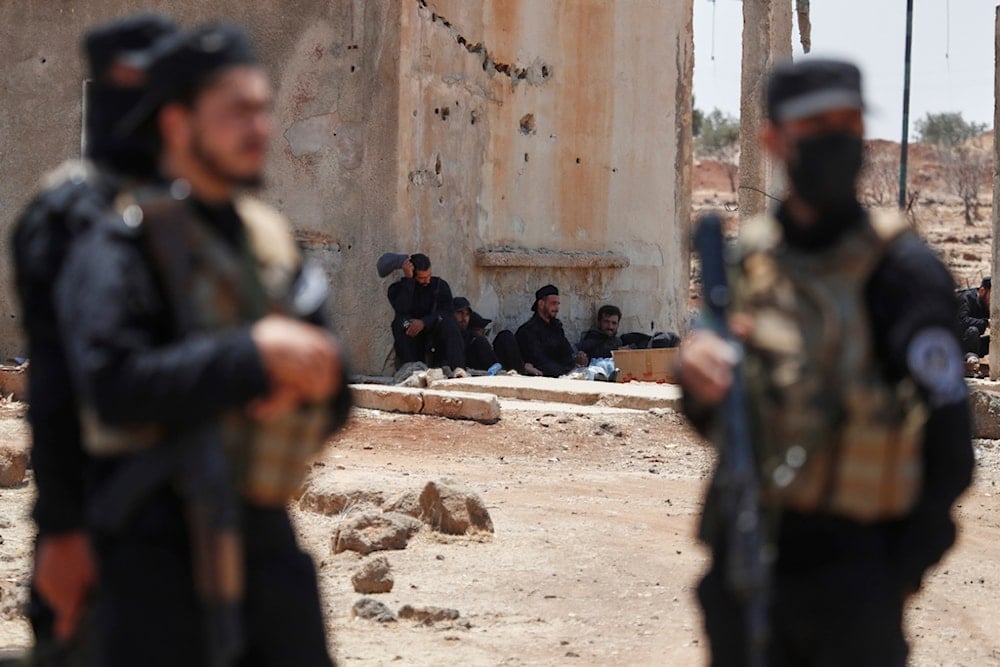 Syrian security forces rest near a damaged building as they deploy in Busra al-Harir village, in southern Syria, Sunday, July 20, 2025 (AP)