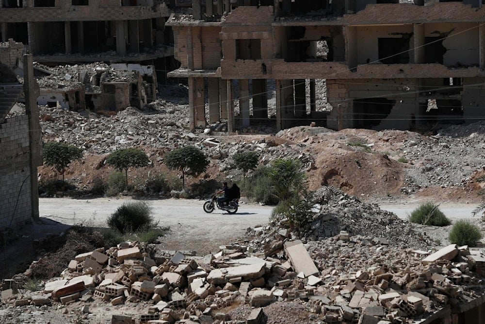 A couple rides a motorcycle past destroyed buildings in Ein Tarma, Monday, Oct. 6, 2025, a suburb of Damascus that was heavily bombed by forces loyal to Syrian President Bashar Assad during the war in Syria (AP)