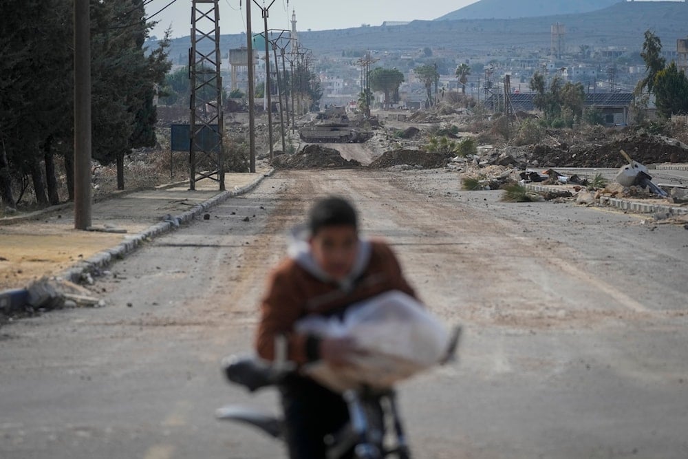 A boy rides his bicycle on a road blocked by Israeli army armoured vehicles in the outskirts of the town of Quneitra, Syria, Sunday Jan. 5, 2025 (AP)