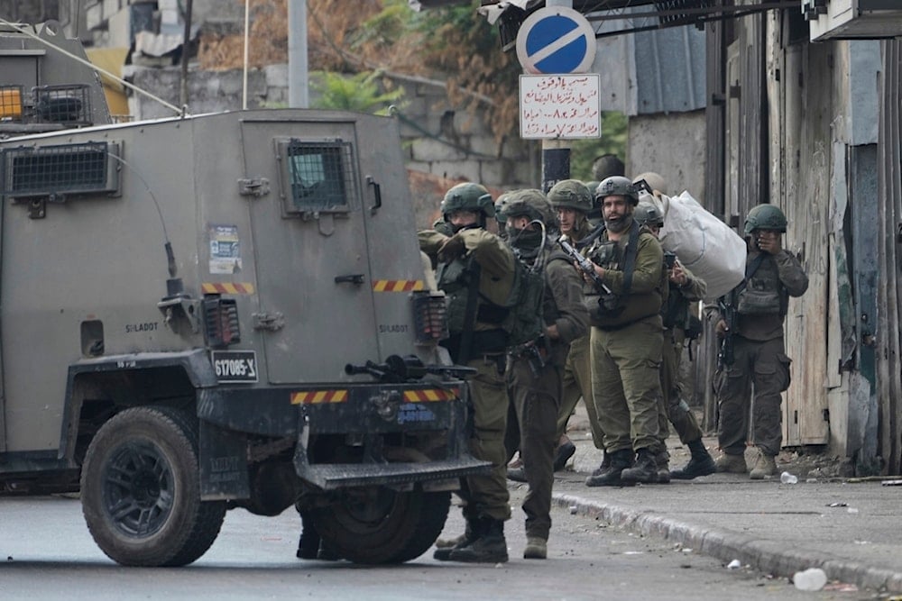 Members of Israeli security forces stand next to an armored vehicle during a military raid in the West Bank city of Nablus, Wednesday, August 27, 2025. (AP Photo/Majdi Mohammed)