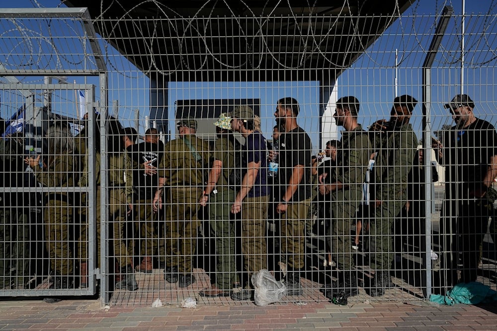  Israeli soldiers gather at the gate to the Sde Teiman military base, as people protest in support of soldiers being questioned for detainee abuse, July 29, 2024 (AP)