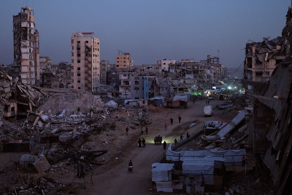 Palestinians walk through the destruction in the Al-Karama neighborhood of Gaza City Sunday, Nov. 30, 2025 (AP)