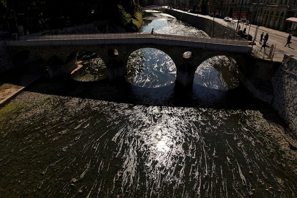 A person walks on a bridge over the Miljacka River, which is almost dried-up with algae visible, amid a heat wave and drought in Sarajevo, Bosnia, Sunday, Aug. 10, 2025 (AP)