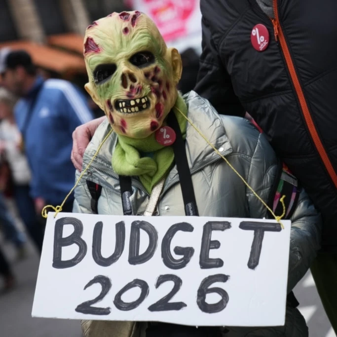 A protester holds a placard reading "Budget 2026" during a demonstration for higher wages and against austerity, in Paris, Tuesday, Dec. 2, 2025. (AP Photo/Christophe Ena)