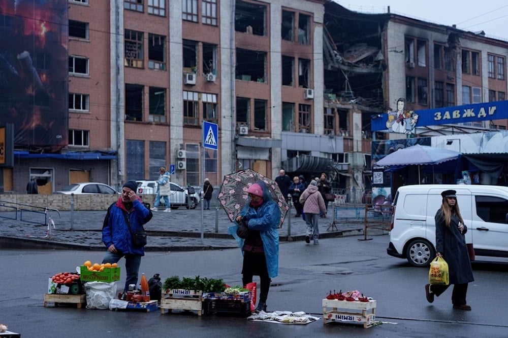 People sell food at the market in front of a building, damaged by a strike, in Kiev, Ukraine, on Monday, Dec. 1, 2025. (AP Photo/Evgeniy Maloletka)