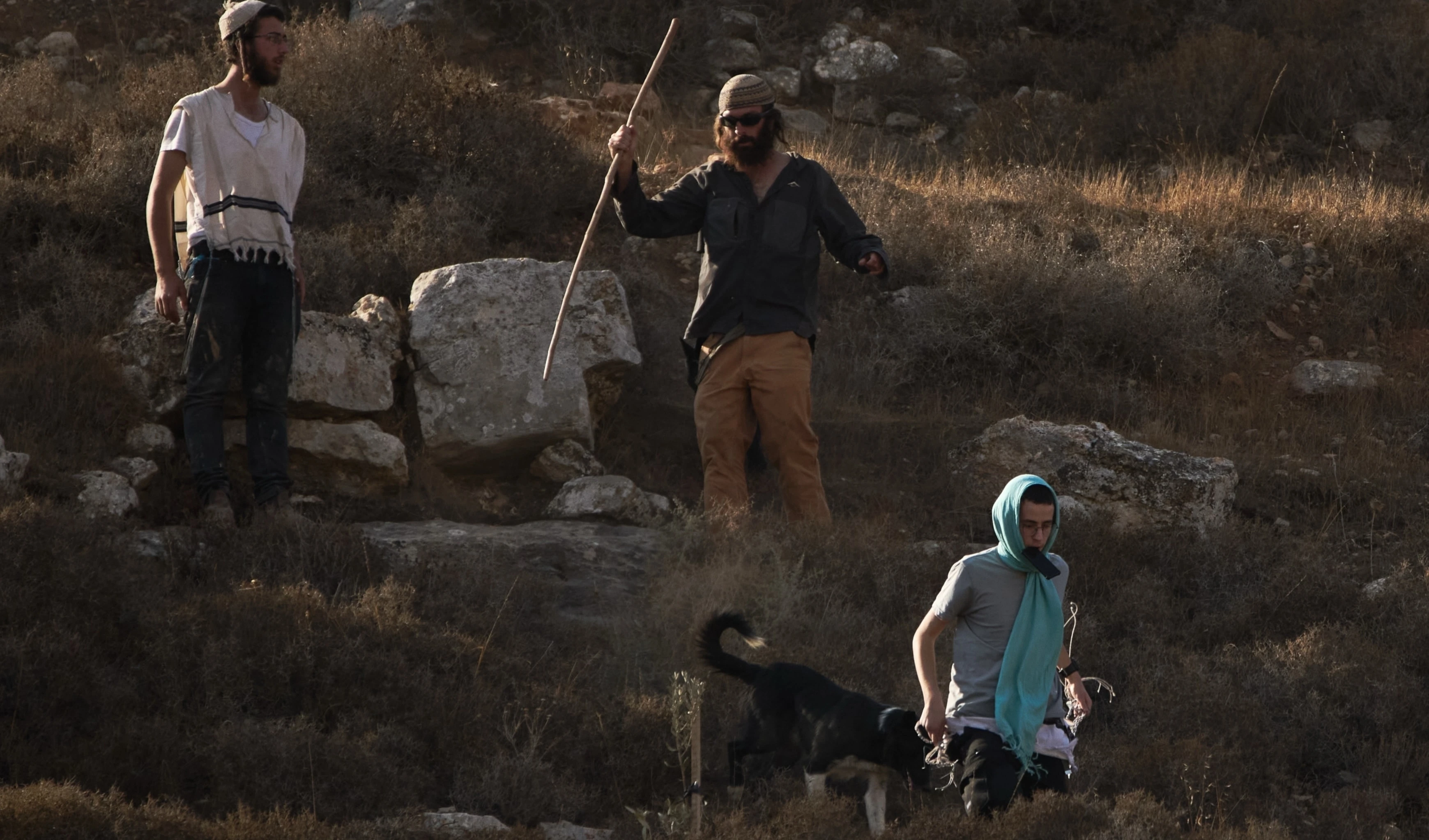 Israeli settlers walk down a hill as Israeli soldiers block access for Palestinians to an area for harvesting olives in the West Bank village of Sa'ir, near al-Khalil, Thursday, Oct. 23, 2025 (AP)