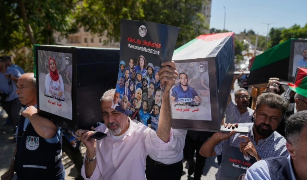 Palestinian journalists carry posters and mock coffins with pictures of their colleagues who were killed during the war on Gaza during a symbolic funeral in the West Bank city of Ramallah, Wednesday, October 8, 2025 (AP)