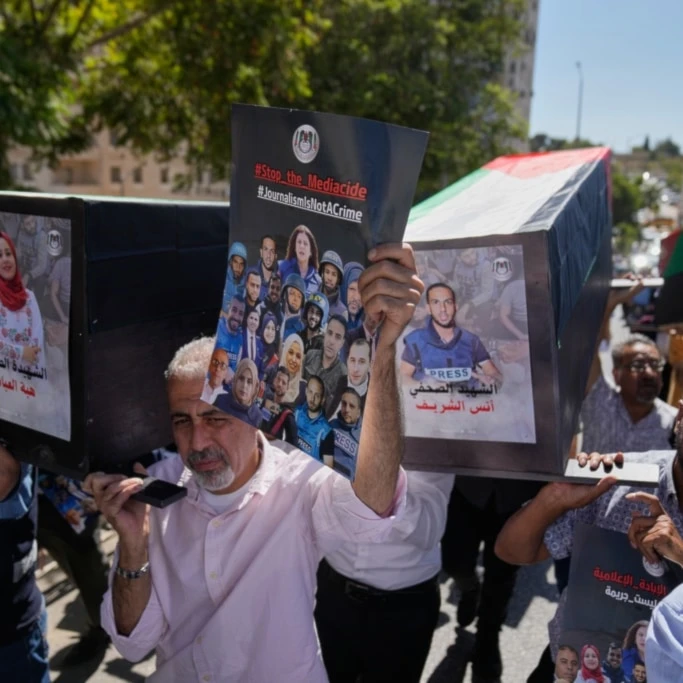 Palestinian journalists carry posters and mock coffins with pictures of their colleagues who were killed during the war on Gaza during a symbolic funeral in the West Bank city of Ramallah, Wednesday, October 8, 2025 (AP)