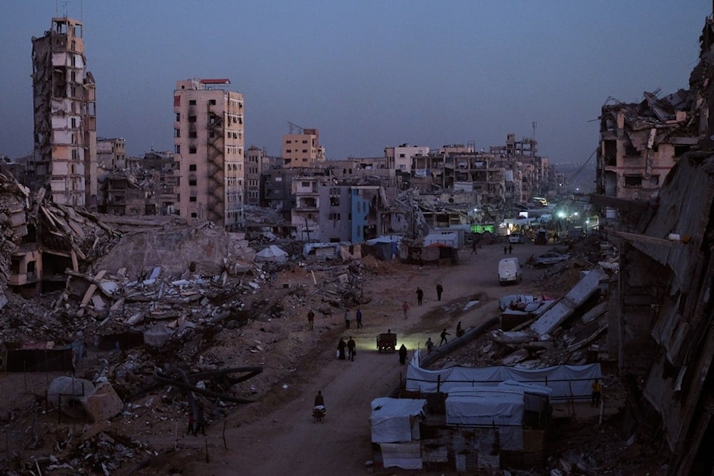 Palestinians walk through the destruction in the al-Karama neighborhood of Gaza City, Sunday, November 30, 2025 (AP)