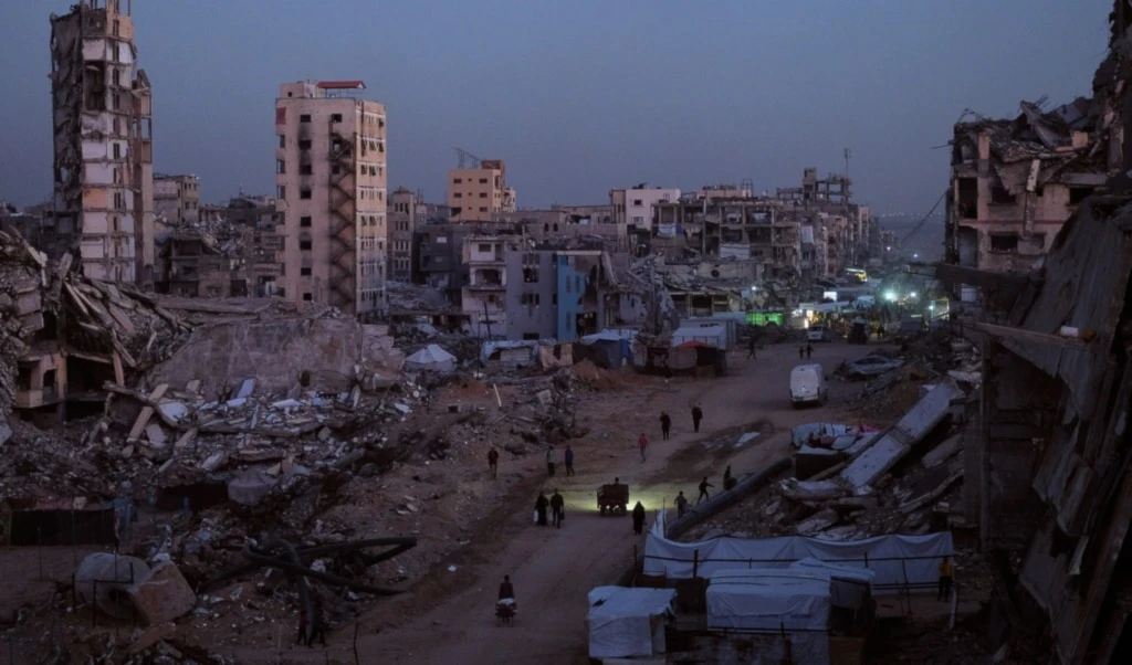 Palestinians walk through the destruction in the al-Karama neighborhood of Gaza City, Sunday, November 30, 2025 (AP)