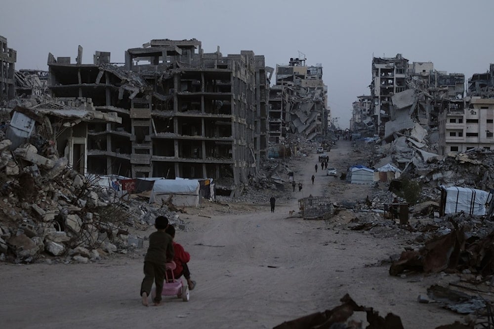 Palestinians walk through the destruction in the al-Karama neighborhood of Gaza City, Sunday, November 30, 2025 (AP)