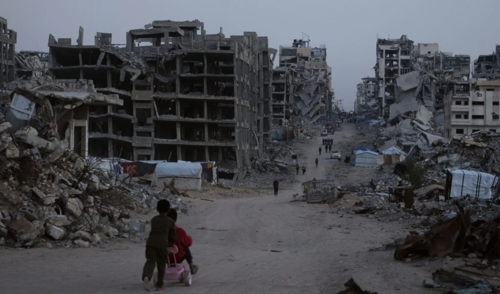 Palestinians walk through the destruction in the al-Karama neighborhood of Gaza City, Sunday, November 30, 2025 (AP)