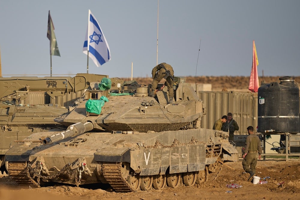 Israeli soldiers work on tanks at a staging area on the border with Gaza Strip, Occupied Palestine, Tuesday, Nov. 18, 2025 (AP)