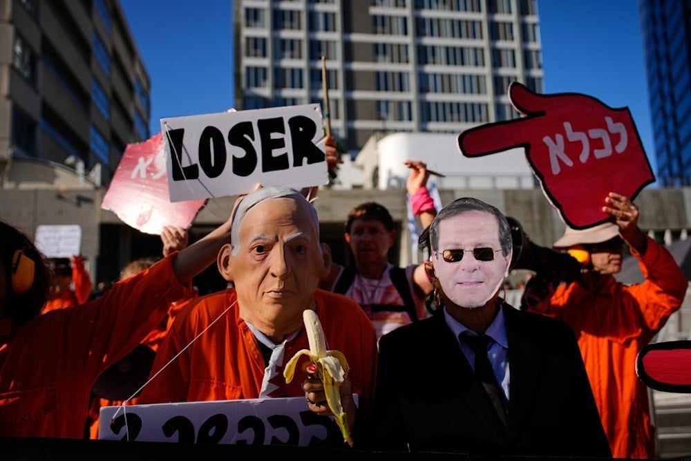 People protest against Israeli Prime Minister Benjamin Netanyahu outside a court in occupied Jaffa on Monday, December 1, 2025, a day after he asked the country's president for a pardon amid his ongoing corruption trial. (AP Photo/Ohad Zwigenberg)
