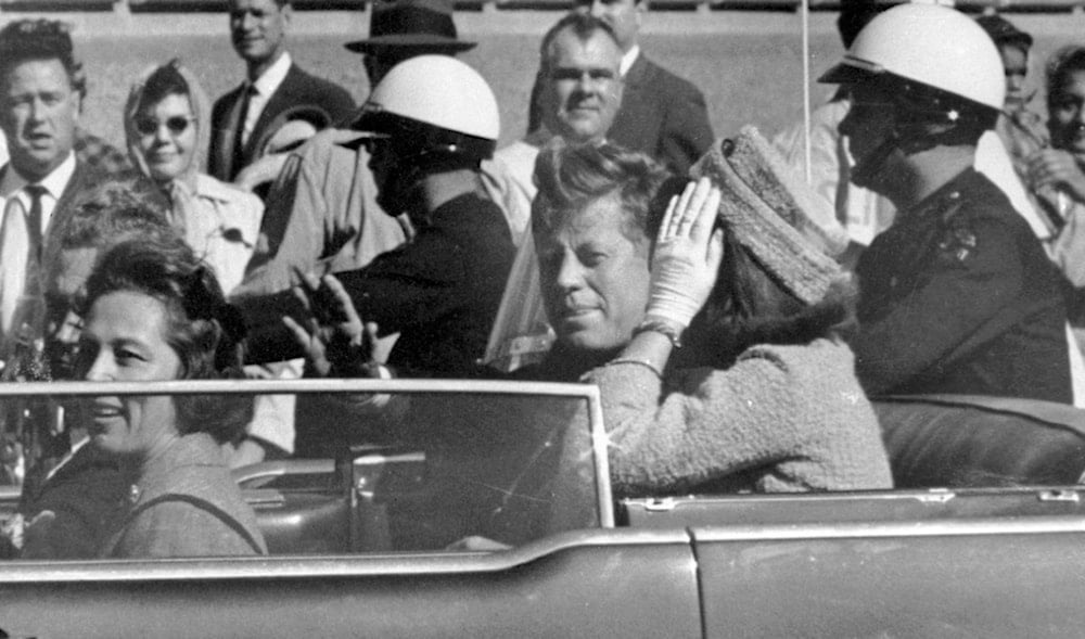 President John F. Kennedy waves from his car in a motorcade approximately one minute before he was shot, Nov. 22, 1963, in Dallas. (AP)