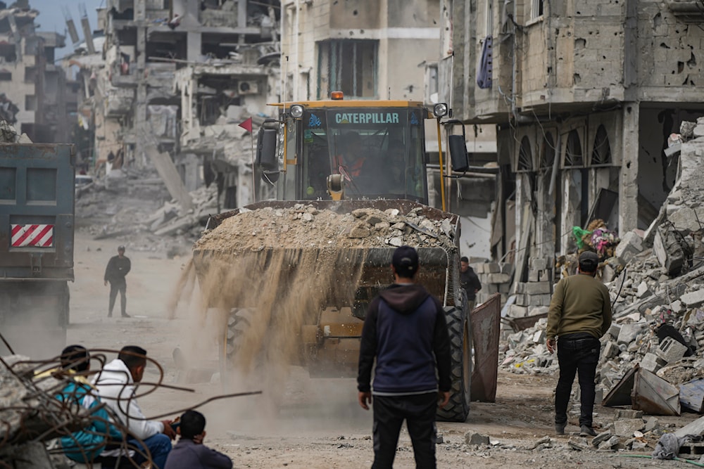  Palestinians watch as a bulldozer clears the rubble of destroyed residential buildings damaged by the Israeli air and ground offensive in Bureij, central Gaza Strip, Wednesday, Jan. 22, 2025. (AP)