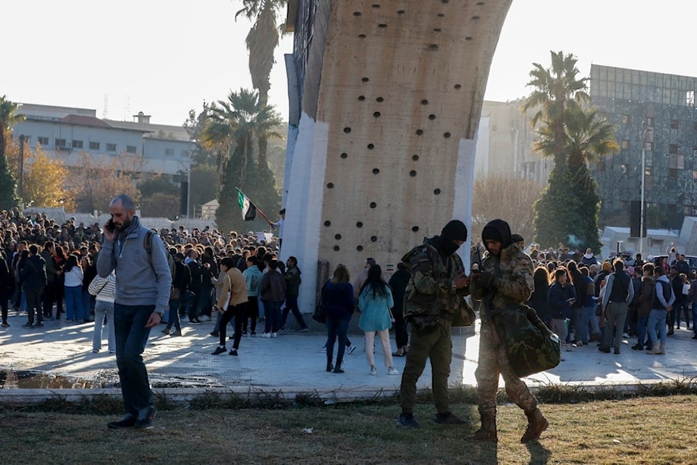 Two Syrian fighters stand guard as activists gather at the Umayyad square during a protest to demand a secular state, in Damascus, Syria, Thursday, Dec. 19, 2024 (AP)