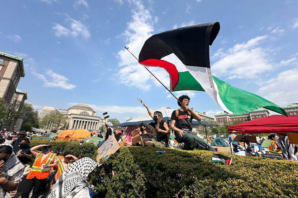 A demonstrator waves a flag on the Columbia University campus at a pro-Palestinian protest encampment, in New York, April 29, 2024 (AP)