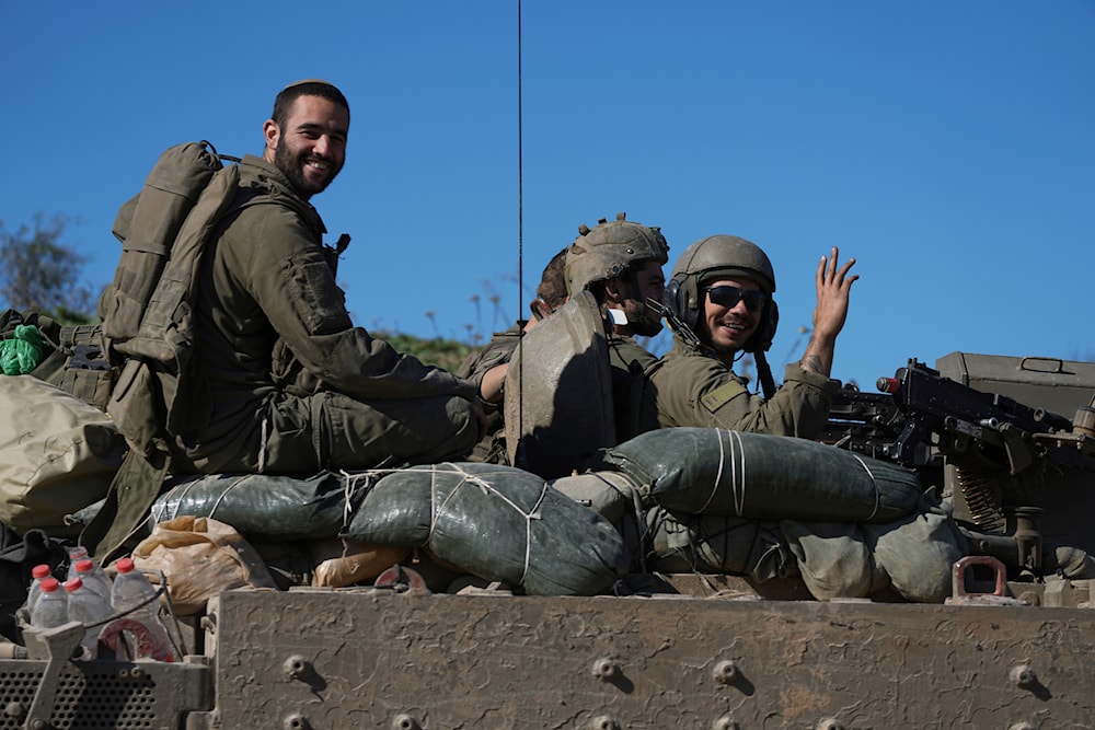  Israeli soldiers wave to the camera from an APC as they cross from the Gaza Strip into 