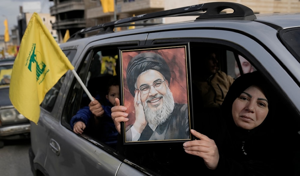 A Lebanese woman holds a portrait of martyred Hezbollah leader Sayyed Hassan Nasrallah, as she sits in a car with her family on their way to check their village in the Bint Jbeil town, south Lebanon, Sunday, Jan. 26, 2025. (AP)