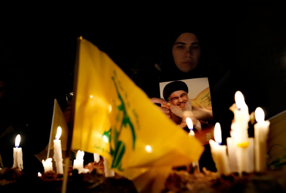 A woman lights candles at the site where former Hezbollah leader Sayyed Hassan Nasrallah was martyred by Israeli airstrikes late September during a memorial ceremony in the southern suburb of Beirut, Lebanon, Saturday, Nov. 30, 2024 (AP)