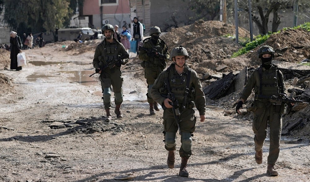Israeli occupation soldiers walk ahead of Palestinians displaced by the Israeli military offensive on the Jenin refugee camp in the West Bank on Thursday, Jan. 23, 2025. (AP)