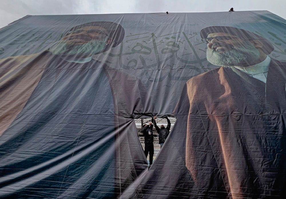 Workers display a giant banner with the portraits of the late Hezbollah leaders Sayyed Hassan Nasrallah and Sayyed Hashem Safieddine at Beirut's City Sportive stadium, in Beirut, Lebanon, Saturday, Feb. 22, 2025 (AP)