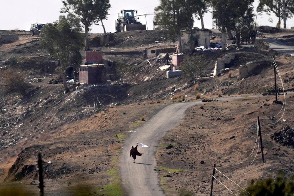 A Syrian man waves a white flag as he approaches Israeli occupation forces where they have set up their new position, in Maariyah, near the border with Israel in southern Syria, Dec. 19, 2024. (AP)