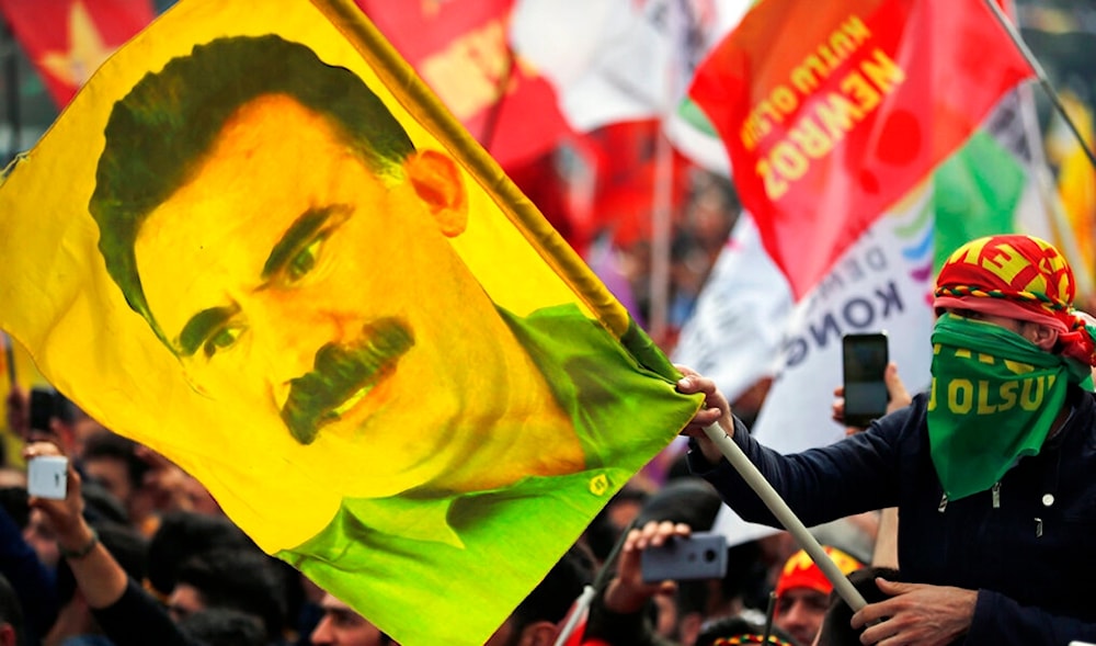 In this file photo dated Wednesday, March 21, 2018, a youth holds a flag with the image of Abdullah Ocalan, the jailed leader of the PKK, in Istanbul, Turkey. (AP)