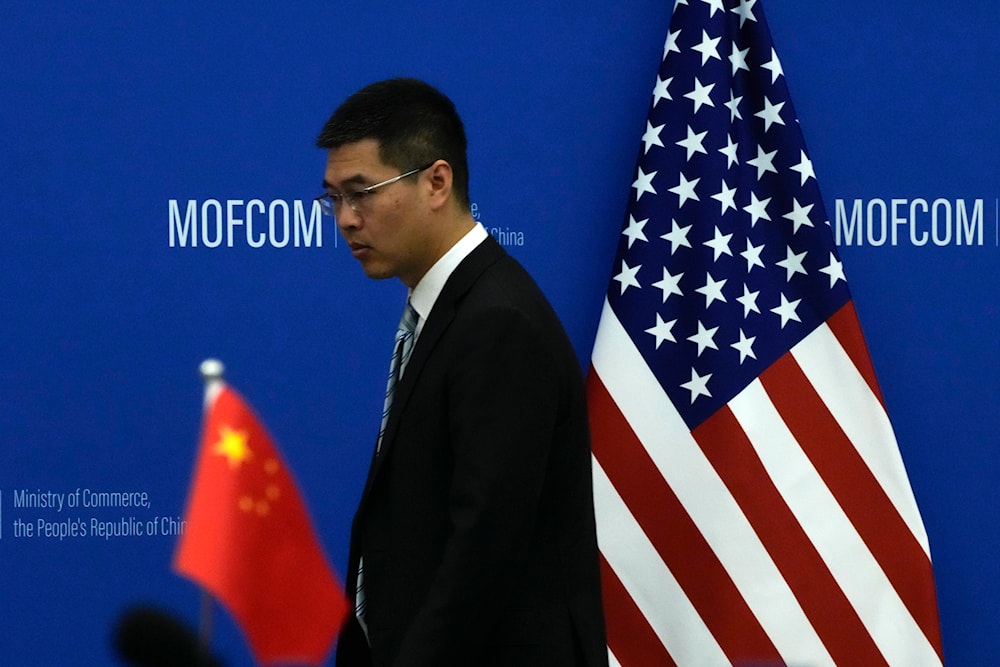 A Chinese official walks by the China and US national flags before a meeting at the Ministry of Commerce in Beijing, Monday, Aug. 28, 2023. (AP)