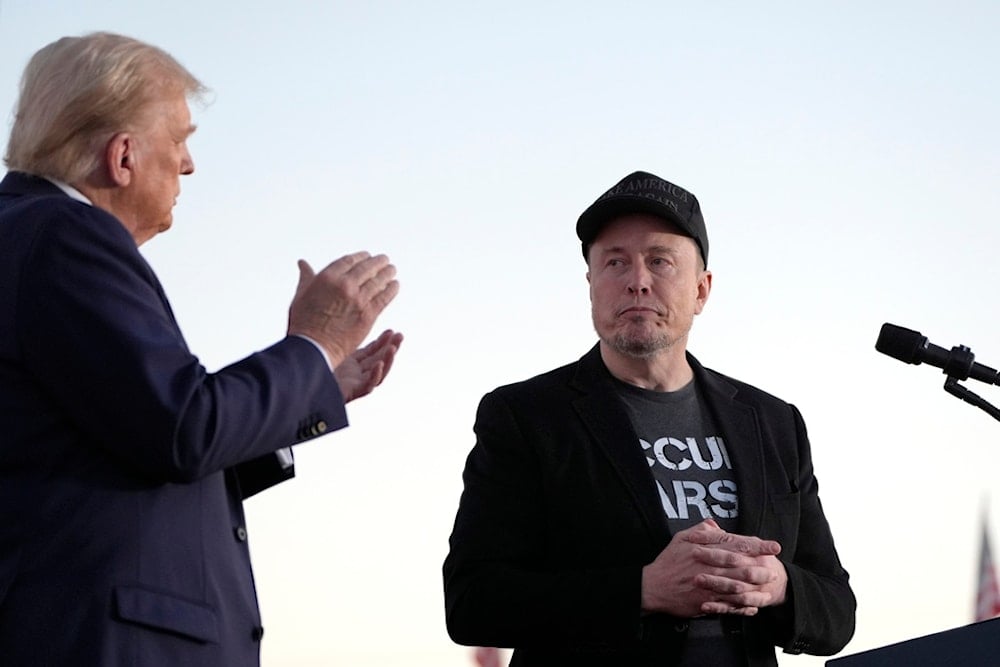 Then-Republican presidential nominee former President Donald Trump, left, claps as Tesla and SpaceX CEO Elon Musk prepares to depart after speaking at a campaign event at the Butler Farm Show, on Oct. 5, 2024, in Butler, Pa (AP)