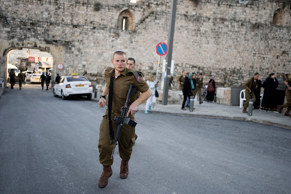 An Israeli occupation forces paratrooper hurries to a swearing-in ceremony at the Western Wall in al-Quds' Old City, Wednesday, January 8, 2025 (AP)