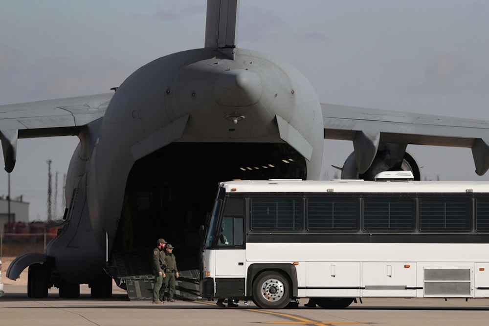 A military aircraft waits for migrants to board from a bus at Fort Bliss in El Paso, Tx., Thursday, Jan. 30, 2025, before deporting them to Guatemala. (AP Photo/Christian Chavez)