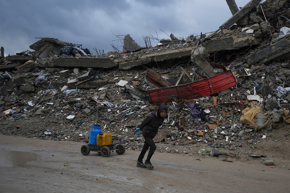 A young Palestinian kid carries water along the destruction caused by the Israeli air and ground aggression in Jabaliya, Gaza Strip, Thursday, Feb. 6, 2025. (AP)